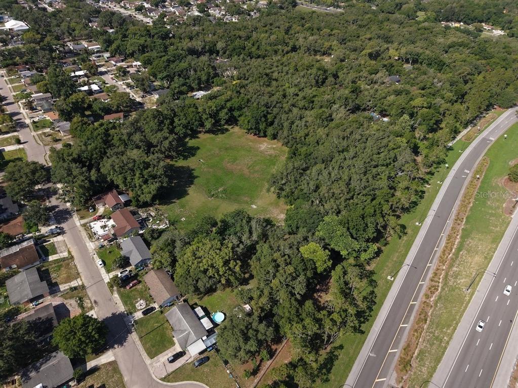 An aerial view shows a large, grassy vacant lot surrounded by trees and residential homes — 481 N LANCELOT AVENUE, ORLANDO, FL