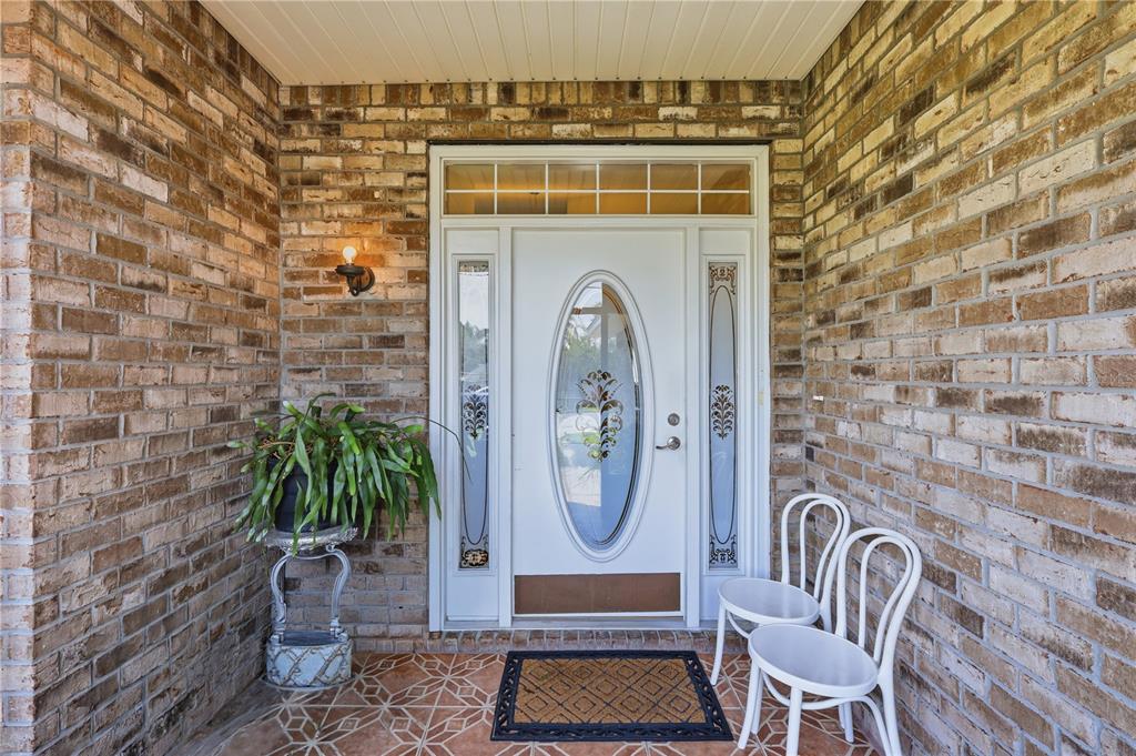 A white front door with an oval glass insert sits between brick walls on a porch — 964 FORT SMITH BOULEVARD, DELTONA, FL