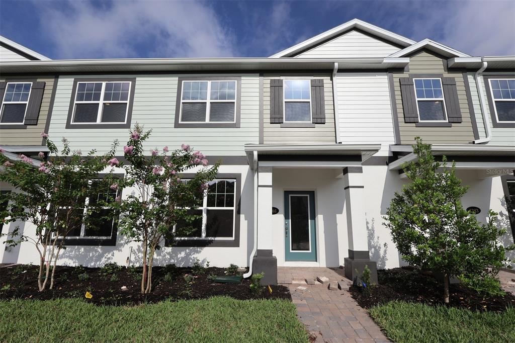 A two-story townhouse exterior features light green and white siding with a covered entryway — 1346 MOUNT ROYAL DRIVE, ST CLOUD, FL