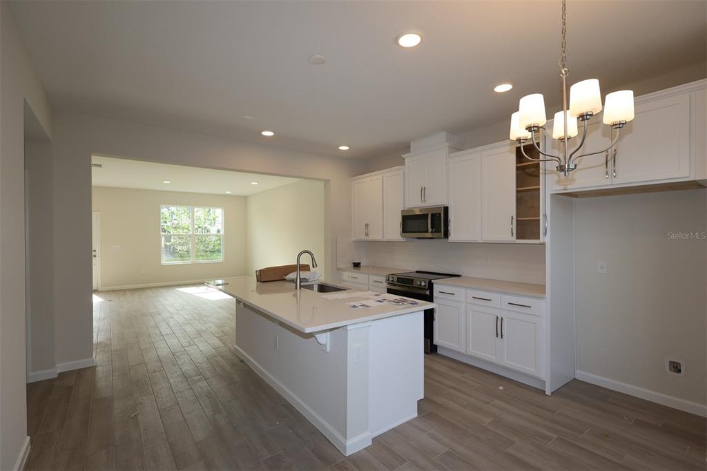 A kitchen with white cabinets, a quartz island, and wood-look tile flooring — 1346 MOUNT ROYAL DRIVE, ST CLOUD, FL