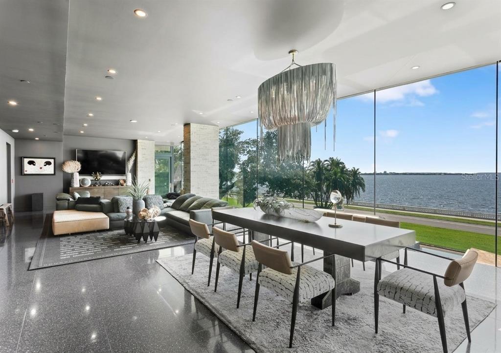 A modern open-concept living and dining area features floor-to-ceiling windows overlooking a large body of water — 2619 BAYSHORE BOULEVARD UNIT 200, TAMPA, FL