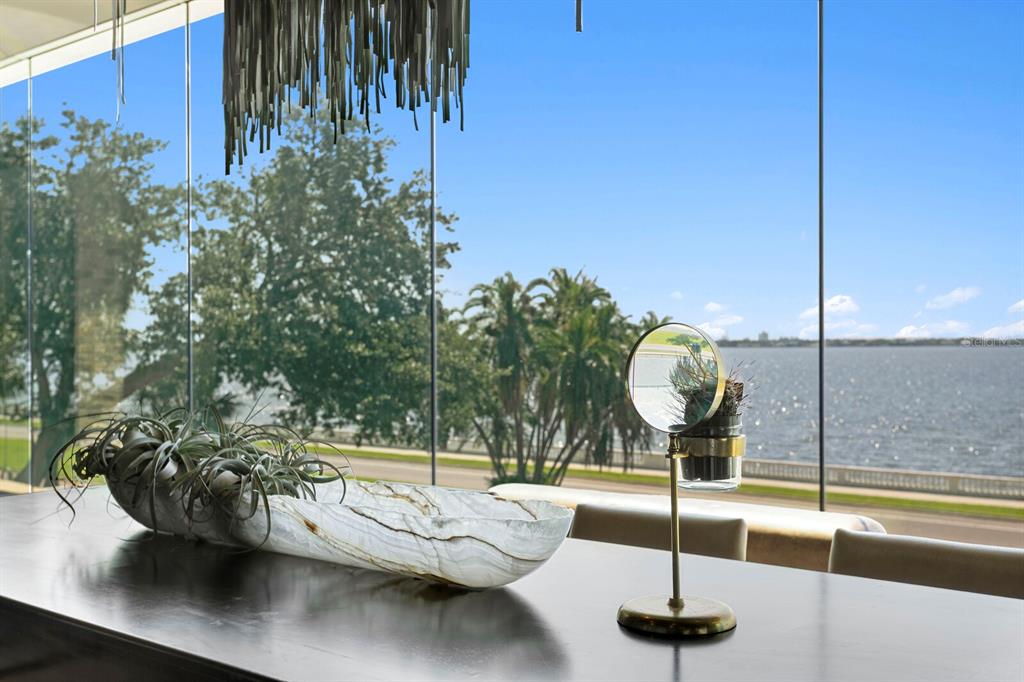 A modern room features a long dark table with a stone bowl and mirror overlooking water — 2619 BAYSHORE BOULEVARD UNIT 200, TAMPA, FL
