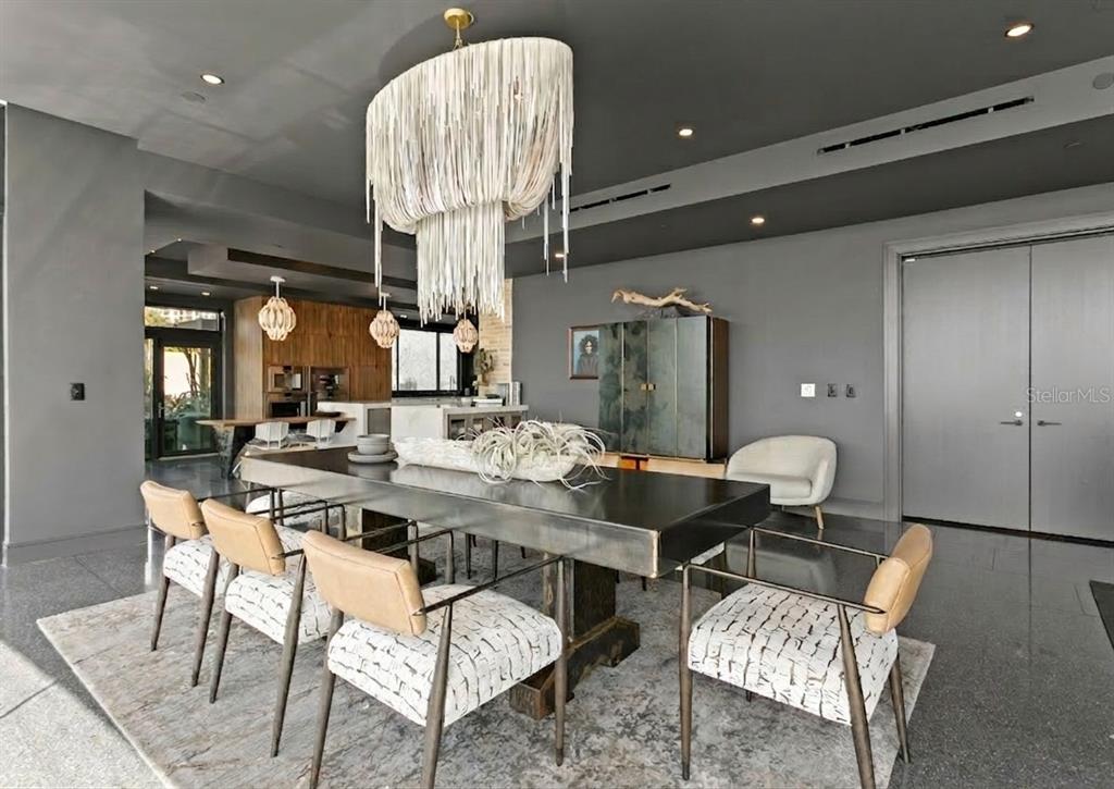 A modern dining room features a large metal table, fringed chandelier, and gray walls — 2619 BAYSHORE BOULEVARD UNIT 200, TAMPA, FL
