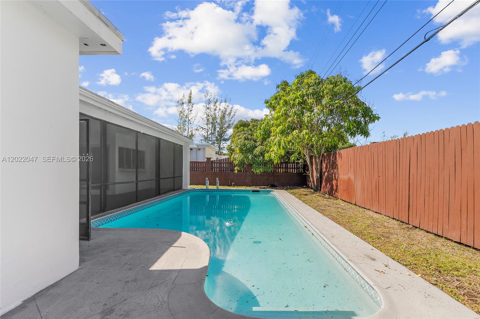 A rectangular swimming pool sits beside a white house with a screened-in patio area — 7773 Coral Blvd, Miramar FL 33023, MIRAMAR, FL
