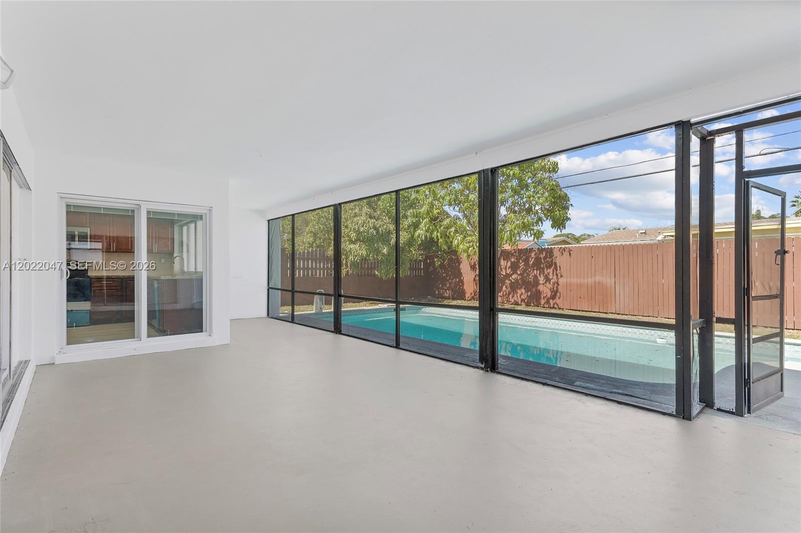 A covered patio features a concrete floor, screen walls, and a view of a pool — 7773 Coral Blvd, Miramar FL 33023, MIRAMAR, FL