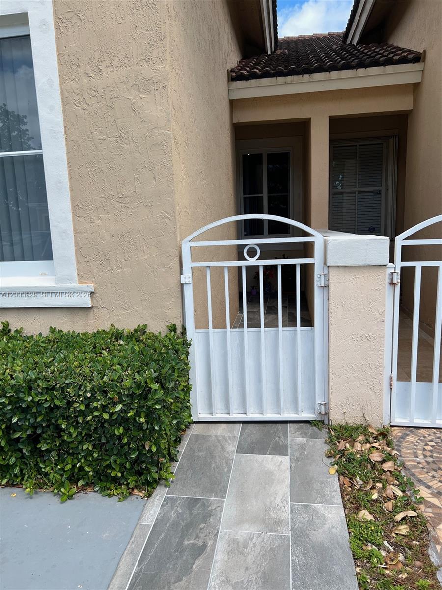 A white metal gate stands at the entrance of a home with tiled flooring — 11021 SW 236th Ter, Homestead FL 33032, HOMESTEAD, FL