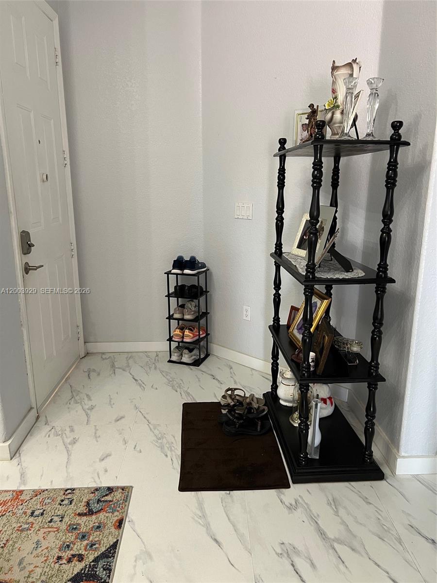 An entryway features white marble-look tile flooring, a black tiered display shelf, and a shoe rack — 11021 SW 236th Ter, Homestead FL 33032, HOMESTEAD, FL
