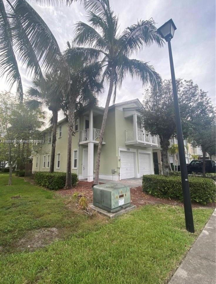 A two-story light green townhouse with a two-car garage and a palm tree in front — 7414 NW 107th Ct # 7414, Doral FL 33178, DORAL, FL