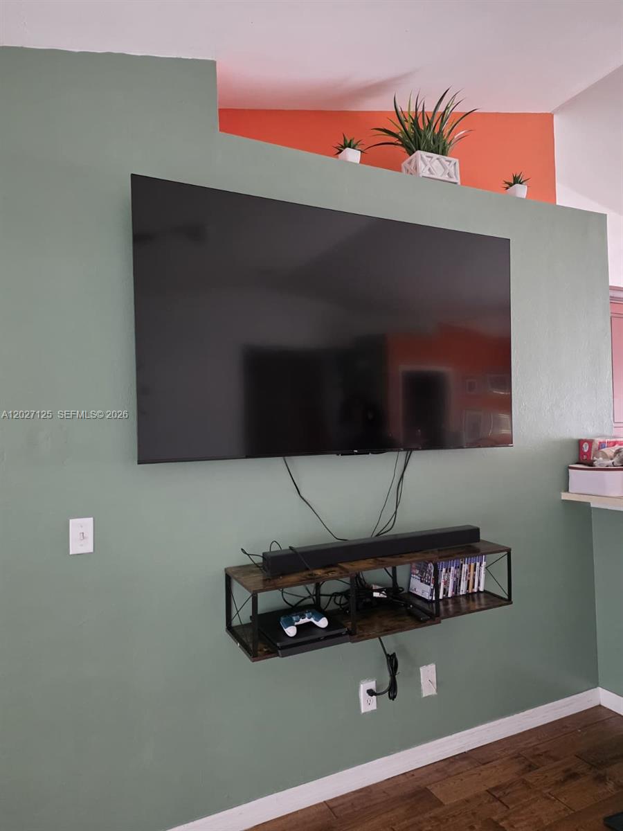 A wall-mounted television sits above a floating shelf on a sage green wall — 3529 Sunshine BLVD, Lehigh Acres FL 33971, LEHIGH ACRES, FL