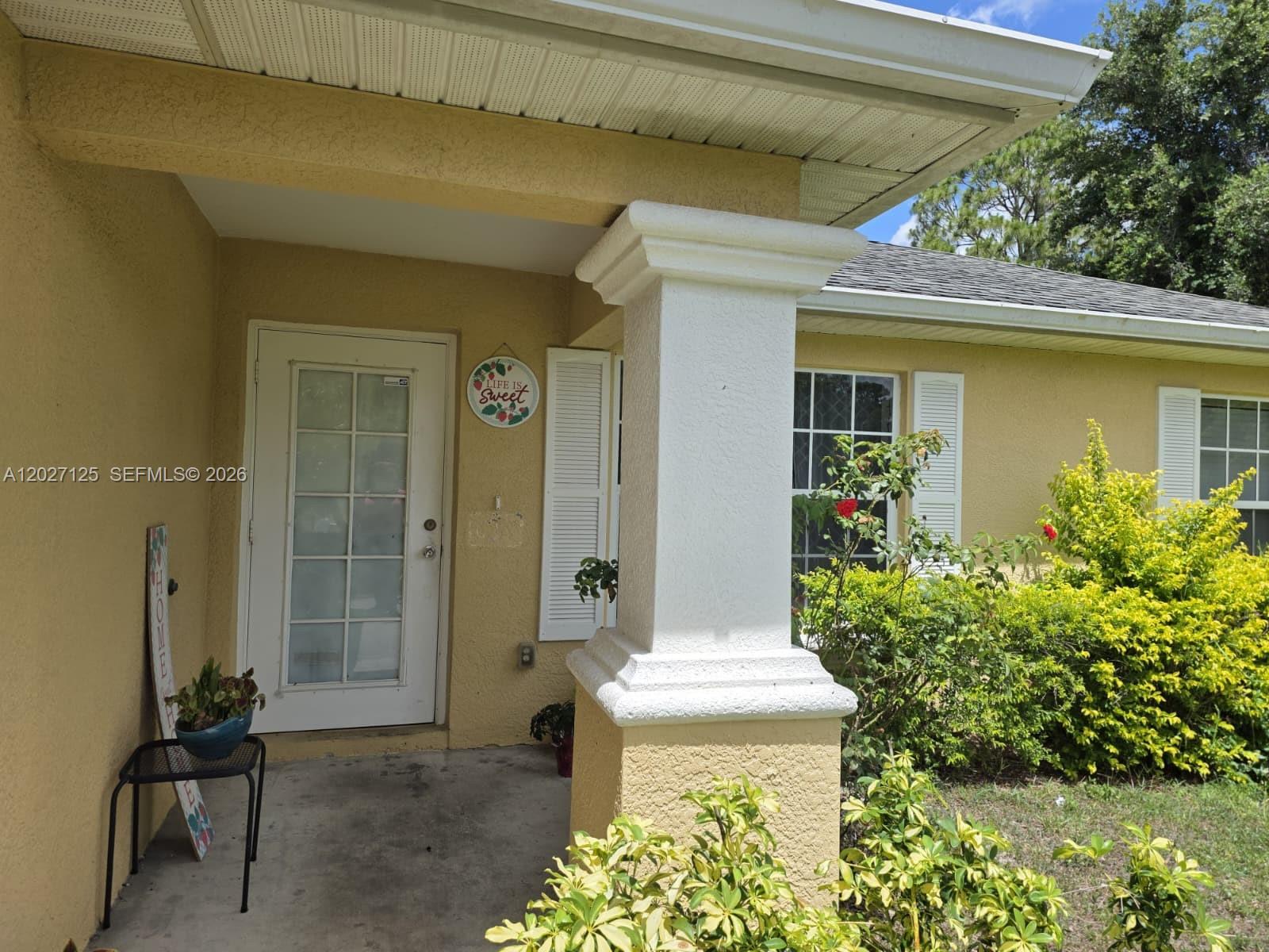 The exterior of a house features a covered porch, a white front door, and a column — 3529 Sunshine BLVD, Lehigh Acres FL 33971, LEHIGH ACRES, FL