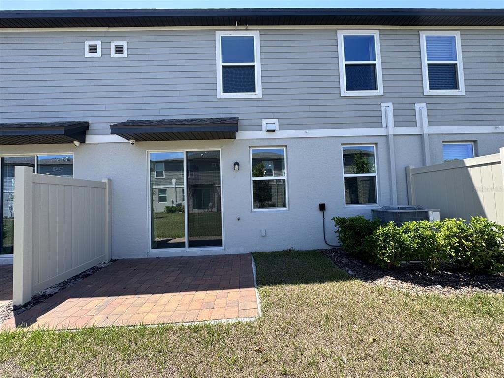 The exterior of a two-story townhouse features a brick patio and a privacy fence — 4532 BURROWING OWL LOOP, ST CLOUD, FL
