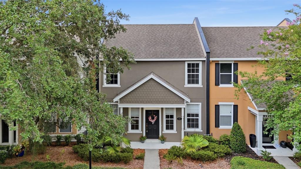 A two-story townhouse with a brown facade, shingled roof, and a small front porch — 809 WYNBROOK LANE, DELAND, FL