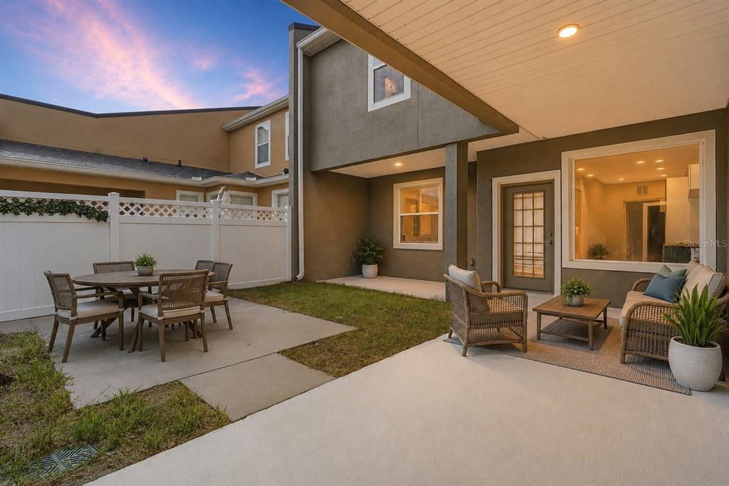 A patio with outdoor furniture, a small lawn, and a white privacy fence at dusk — 809 WYNBROOK LANE, DELAND, FL
