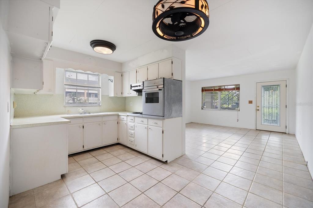 A white kitchen with tile floors and a built-in oven opens to a living area — 450 32ND AVENUE N UNIT 106W, ST PETERSBURG, FL