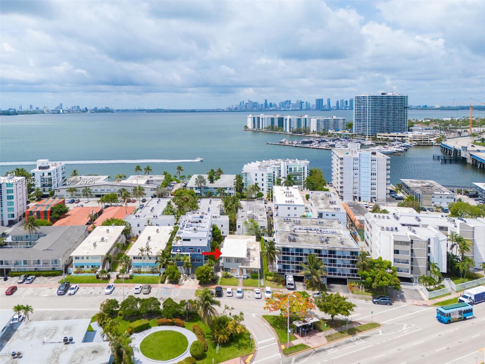An aerial view shows a multi-story apartment building complex near a waterfront with a city skyline — 1980 Biarritz Dr, Miami Beach FL 33141, MIAMI BEACH, FL