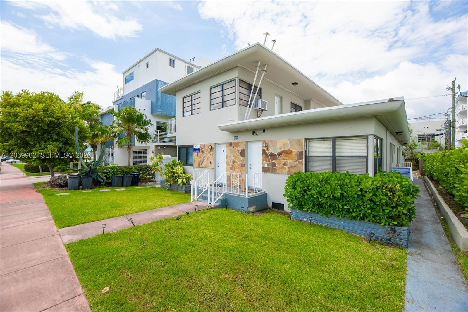 A two-story apartment building features a stone facade, white doors, and a green lawn — 1980 Biarritz Dr, Miami Beach FL 33141, MIAMI BEACH, FL