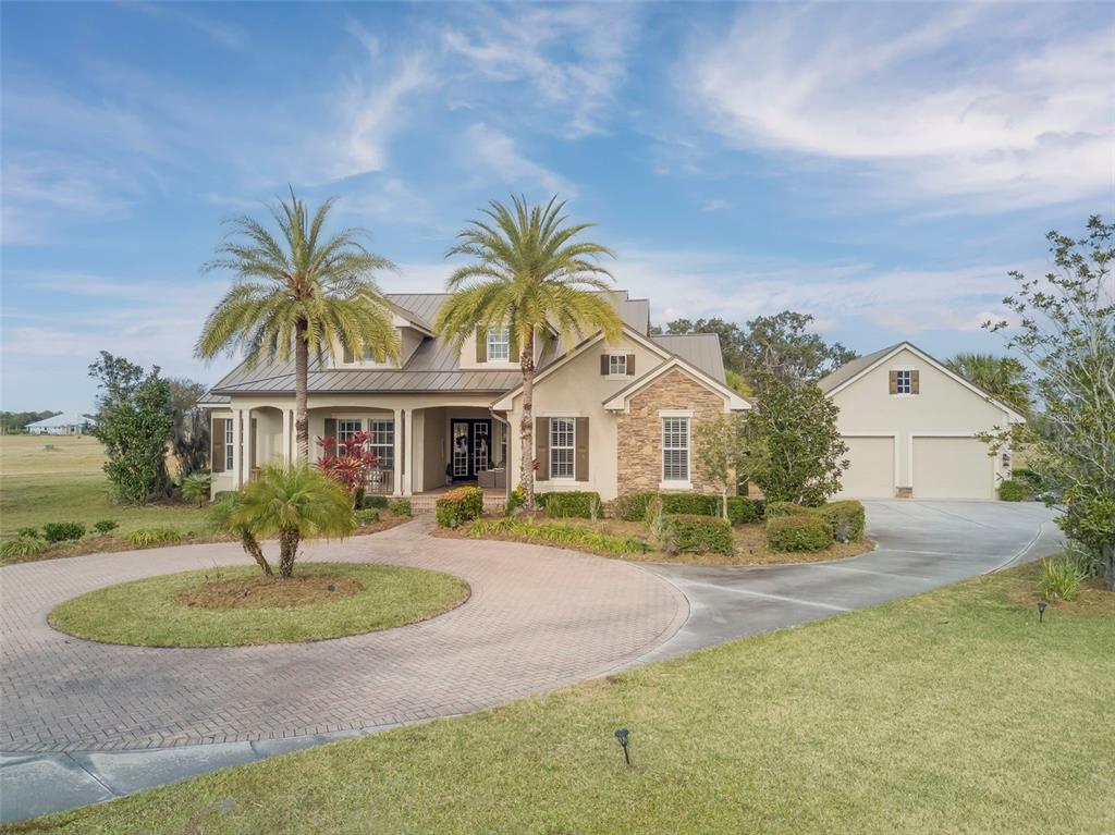 A two-story house with a circular brick driveway, palm trees, and an attached garage — 2131 SILK BAY BOULEVARD, ALVA, FL