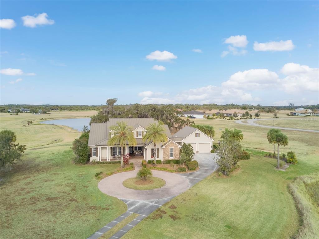 An aerial view shows a two-story house with a circular driveway and a metal roof — 2131 SILK BAY BOULEVARD, ALVA, FL