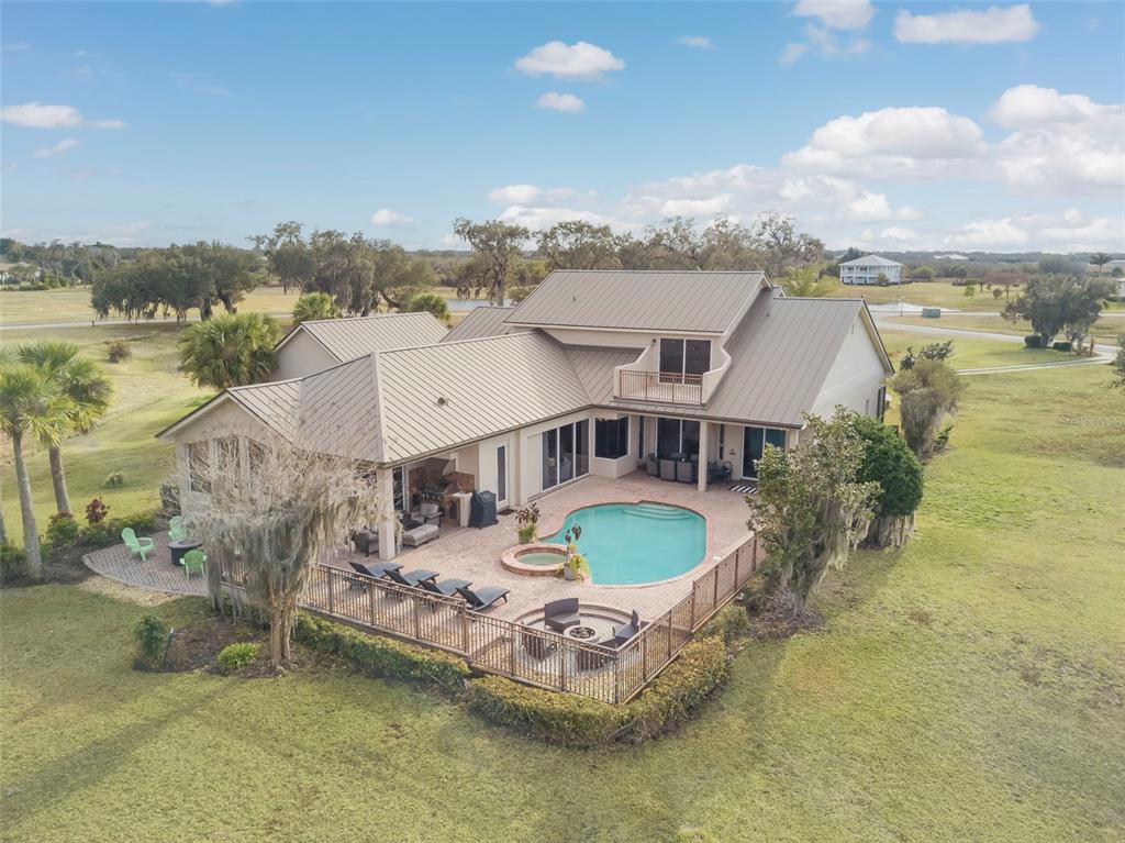 An aerial view of a house with a metal roof, pool, and fenced patio area — 2131 SILK BAY BOULEVARD, ALVA, FL