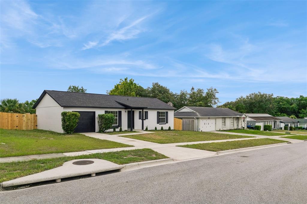 A single-story white house with a black roof and garage sits on a suburban street — 3117 KNIGHTSBRIDGE ROAD, ORLANDO, FL
