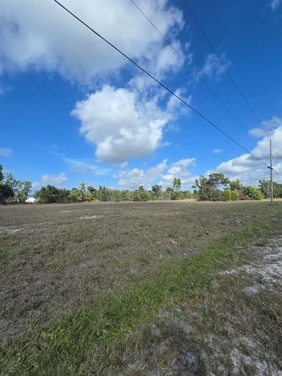 A flat, grassy vacant lot under a blue sky with power lines overhead — 3813 NW 46TH LANE, CAPE CORAL, FL