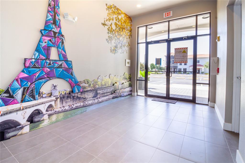 A lobby features a large mural of the Eiffel Tower and glass double doors — 4290 S HIGHWAY 27 UNIT 206, CLERMONT, FL