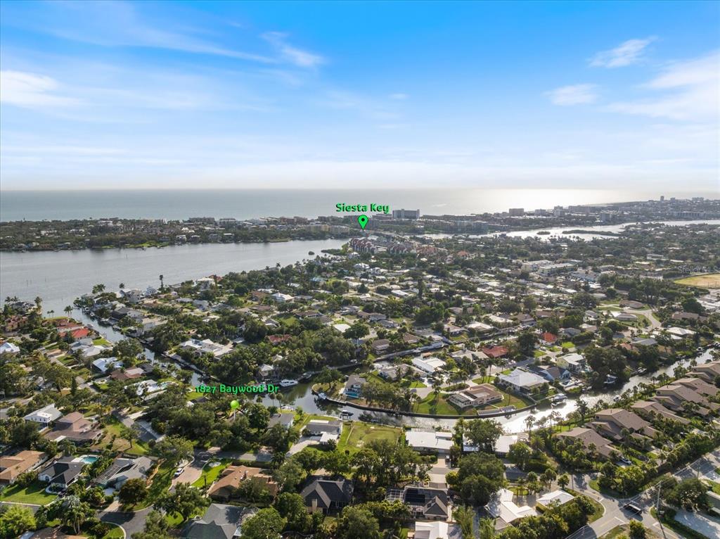 An aerial view shows a residential neighborhood with canals leading toward the ocean — 1827 BAYWOOD DRIVE, SARASOTA, FL