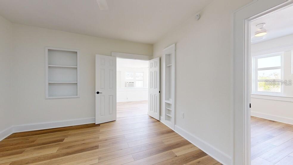An interior room features white walls, light wood flooring, built-in shelving, and open doorways — 218 N PINELLAS AVENUE, TARPON SPRINGS, FL
