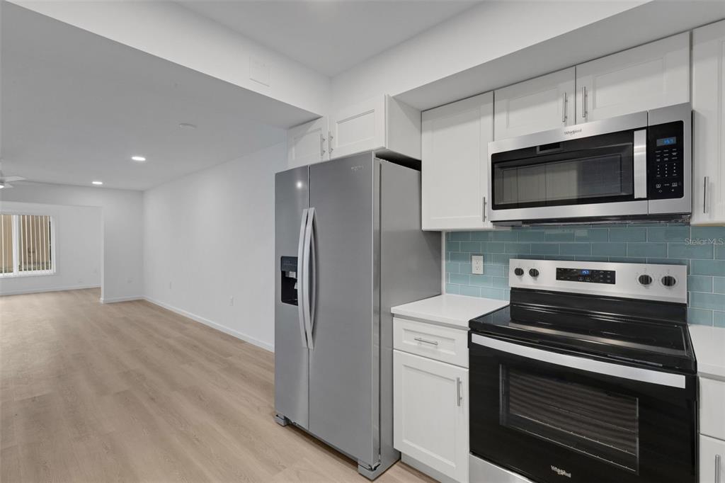 A kitchen features white cabinets, stainless steel appliances, and a light blue tiled backsplash — 2826 W RAINBOW CIRCLE UNIT 2818, SARASOTA, FL
