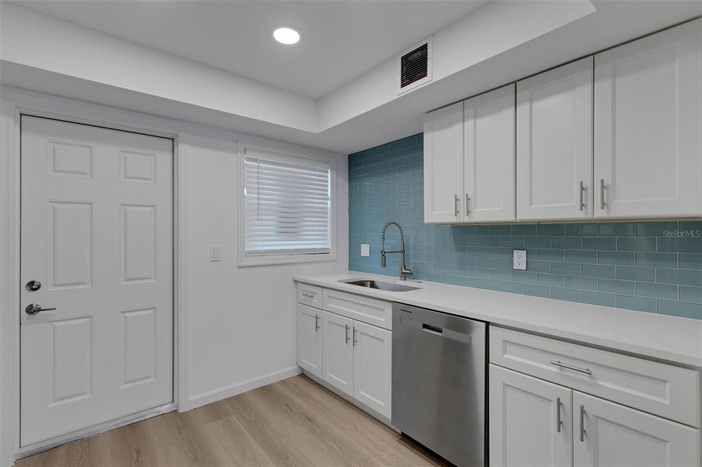 A kitchen features white cabinets, a blue subway tile backsplash, and stainless steel appliances — 2826 W RAINBOW CIRCLE UNIT 2818, SARASOTA, FL