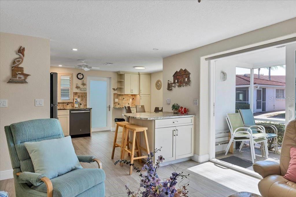 A kitchen with light cabinets and a center island opens to a covered patio area — 6154 MIDNIGHT PASS ROAD UNIT C08, SARASOTA, FL