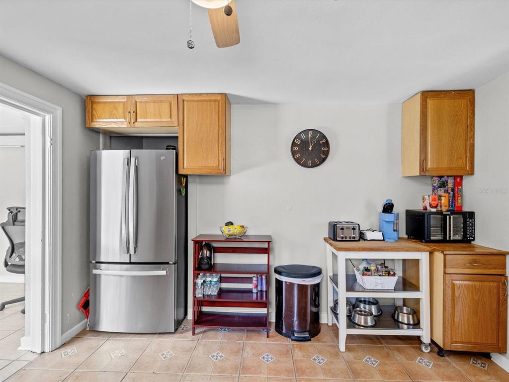 A kitchen area features a stainless steel refrigerator, wooden cabinets, and a small dining table — 5015 15TH AVENUE S, GULFPORT, FL