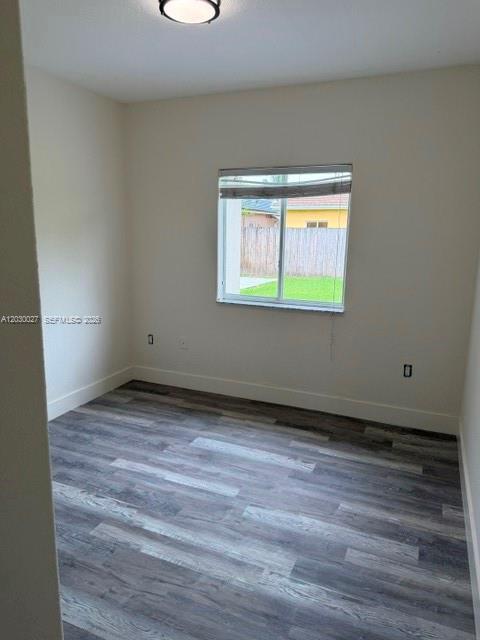 An empty bedroom features light-colored walls, gray wood-look flooring, and a single window — 706 SE 14th Ave, Homestead FL 33033, HOMESTEAD, FL