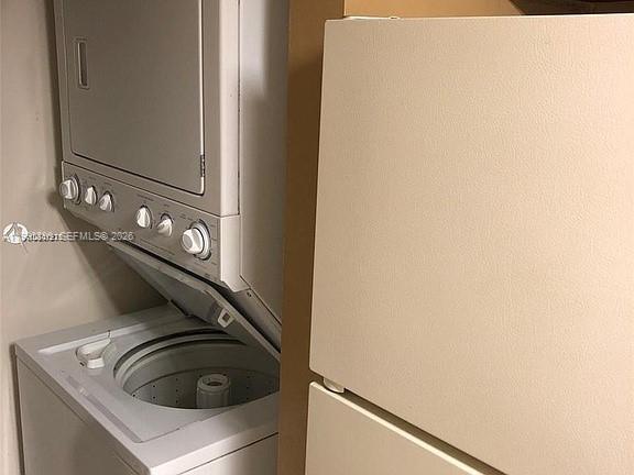 A white stacked washer and dryer unit sits next to a beige refrigerator — 7235 NW 179th St # 103, Hialeah FL 33015, HIALEAH, FL