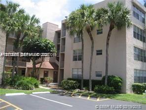 A multi-story apartment building with beige stucco walls and palm trees in the foreground — 9470 Live Oak Pl # 306, Davie FL 33324, DAVIE, FL