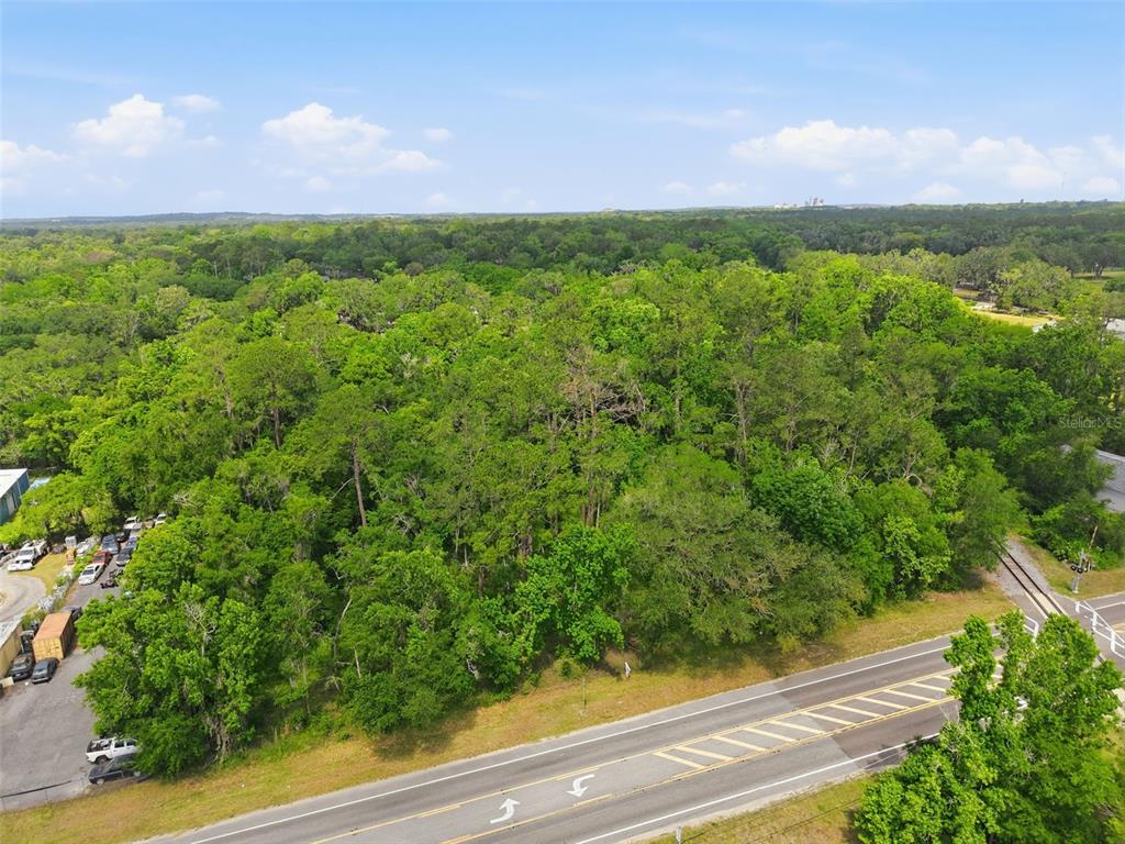 An aerial view shows a dense, wooded lot adjacent to a paved road and railroad tracks — PONCE DE LEON BOULEVARD, BROOKSVILLE, FL