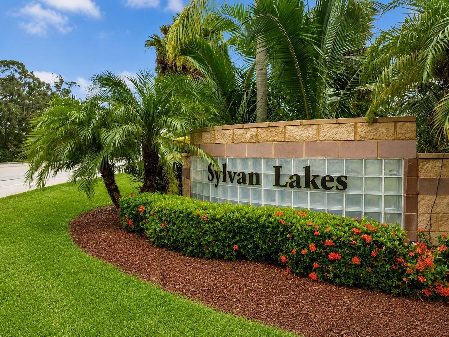 A stone and glass block sign for Sylvan Lakes sits in a landscaped garden bed — 5850 39th Ln Lane, Vero Beach FL 32966, VERO BEACH, FL
