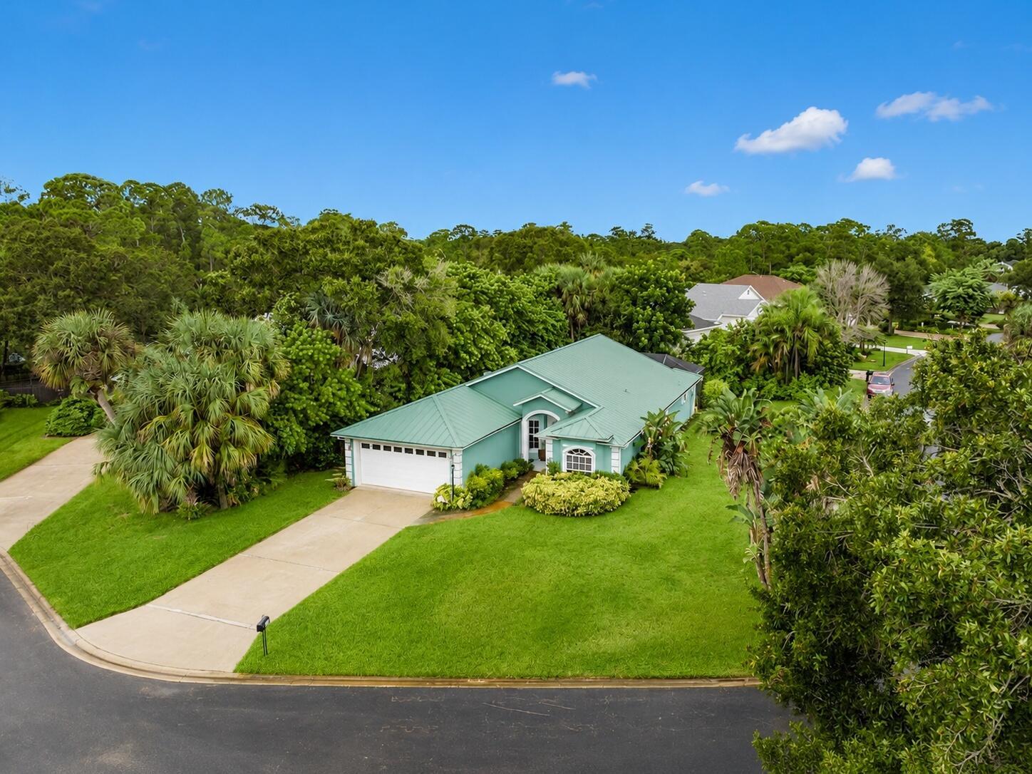 An aerial view of a teal, single-story house with a metal roof and a driveway — 5850 39th Ln Lane, Vero Beach FL 32966, VERO BEACH, FL