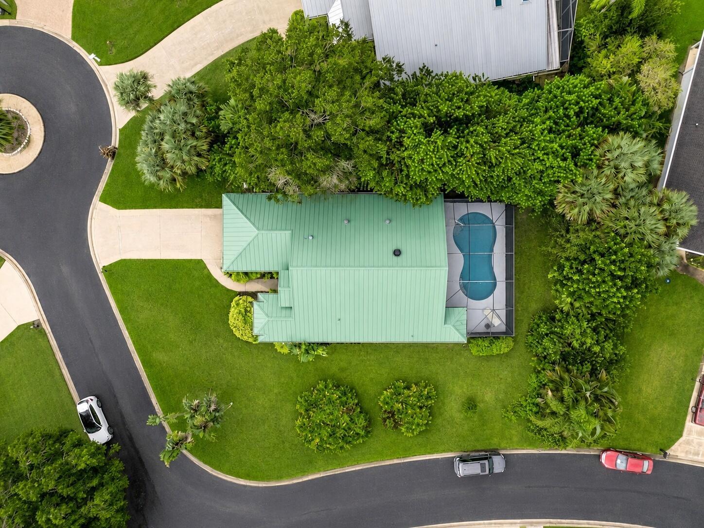 An aerial view shows a house with a green metal roof and a screened-in pool — 5850 39th Ln Lane, Vero Beach FL 32966, VERO BEACH, FL