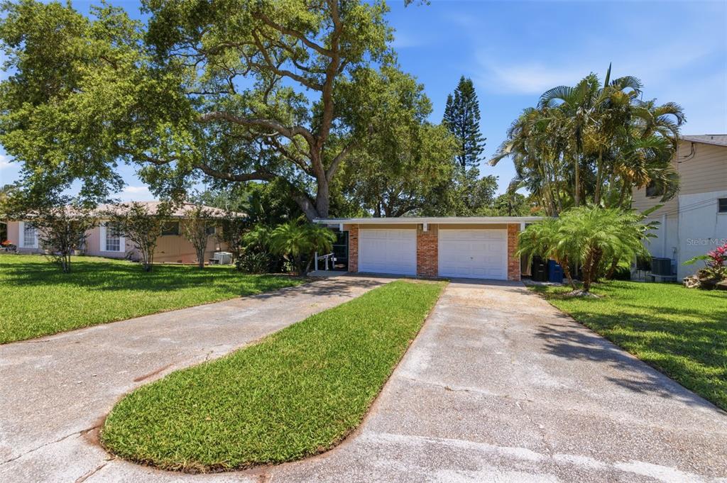 A two-car garage with a split concrete driveway and a large tree in the front yard — 1918 BYRAM DRIVE, CLEARWATER, FL