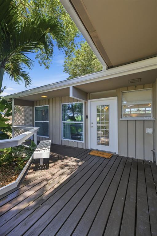 A wooden deck leads to a white front door with a glass pane and windows — 1918 BYRAM DRIVE, CLEARWATER, FL