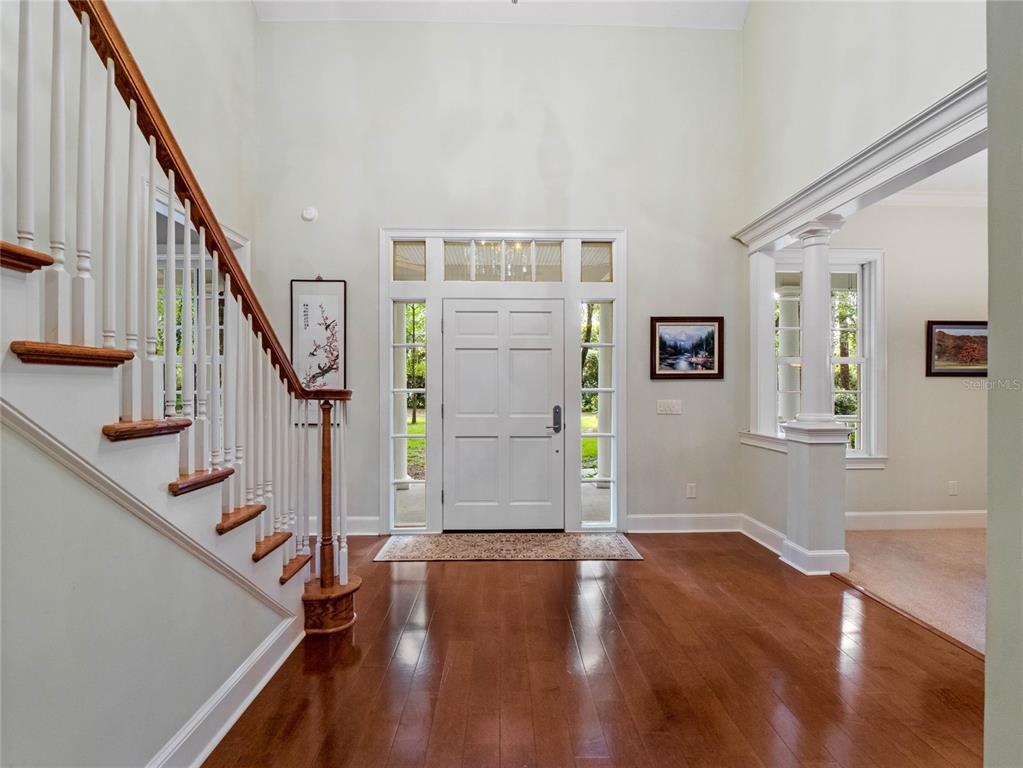 A bright foyer features hardwood floors, a white staircase, and a central front door — 4000 ROUSE ROAD, ORLANDO, FL
