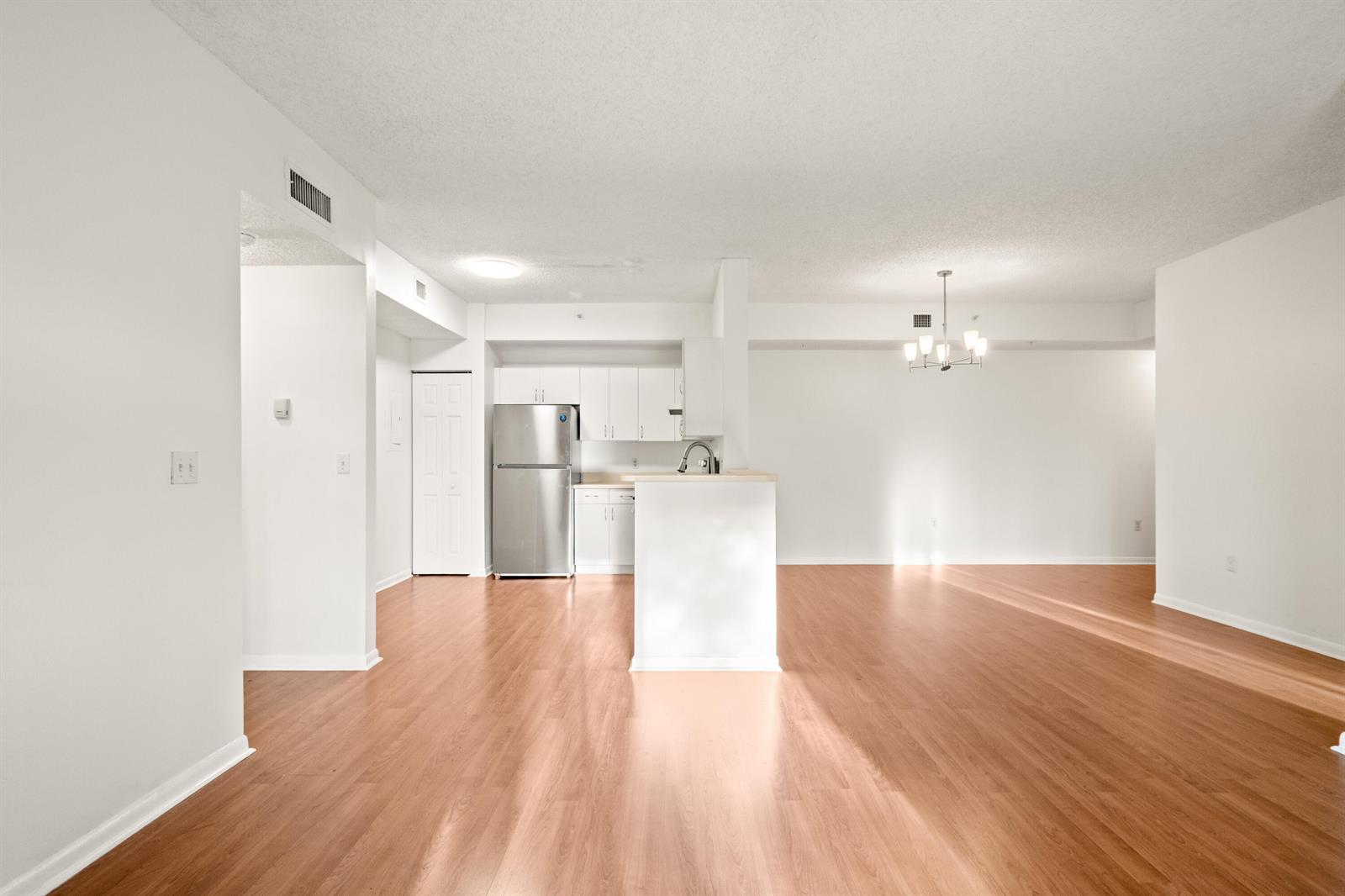 An open-concept kitchen with stainless steel appliances and wood-look flooring flows into a dining area — 6960 SW 39th # E205, Davie FL 33314, DAVIE, FL