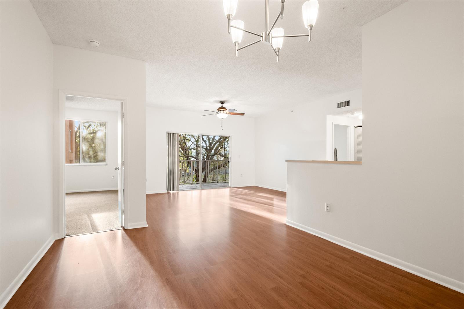 An empty living room with wood-look flooring, a ceiling fan, and a sliding glass door — 6960 SW 39th # E205, Davie FL 33314, DAVIE, FL