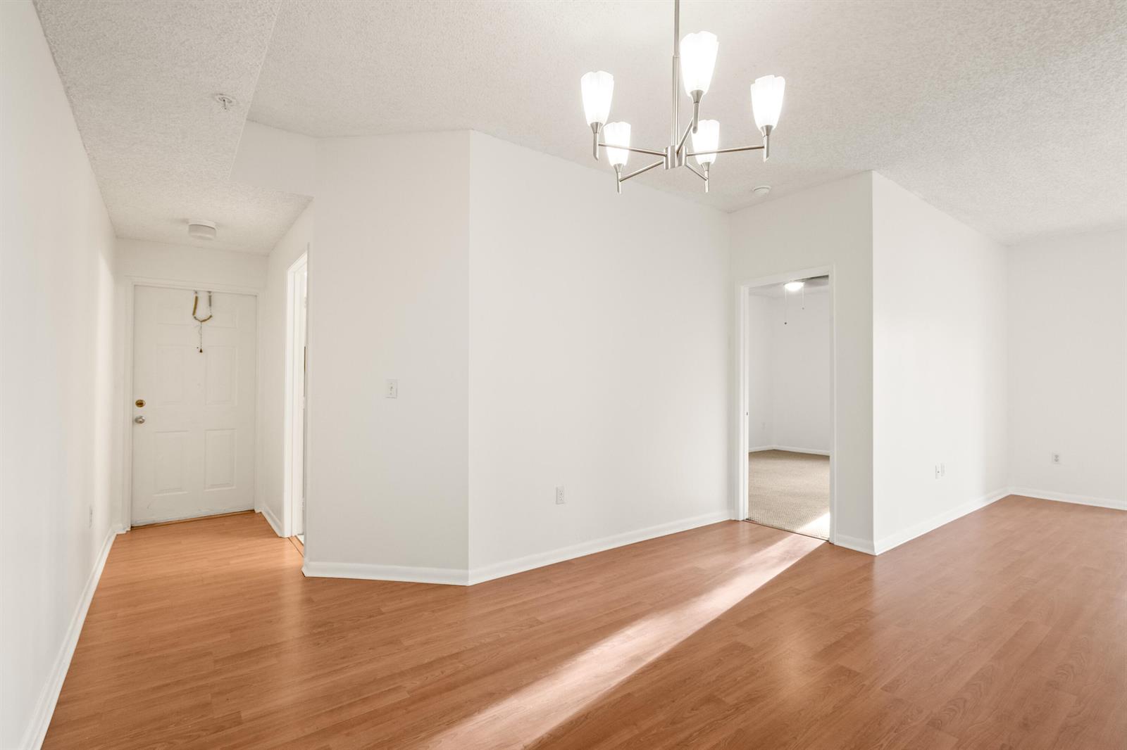 An empty room with wood-look flooring, white walls, and a modern chandelier — 6960 SW 39th # E205, Davie FL 33314, DAVIE, FL
