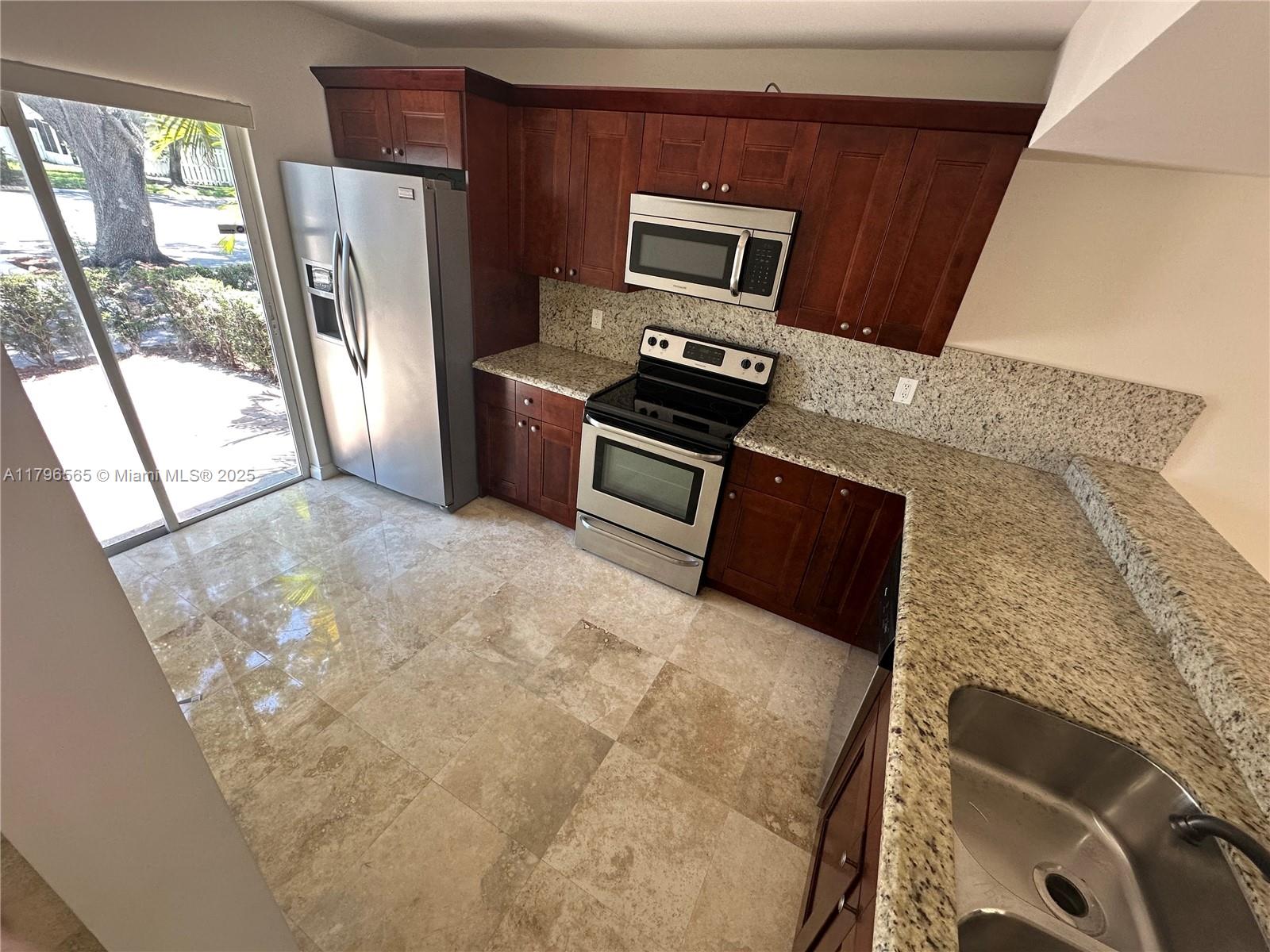 A kitchen features dark wood cabinets, granite countertops, stainless steel appliances, and tile flooring — 878 Crystal Lake Dr, Deerfield Beach FL 33064, DEERFIELD BEACH, FL