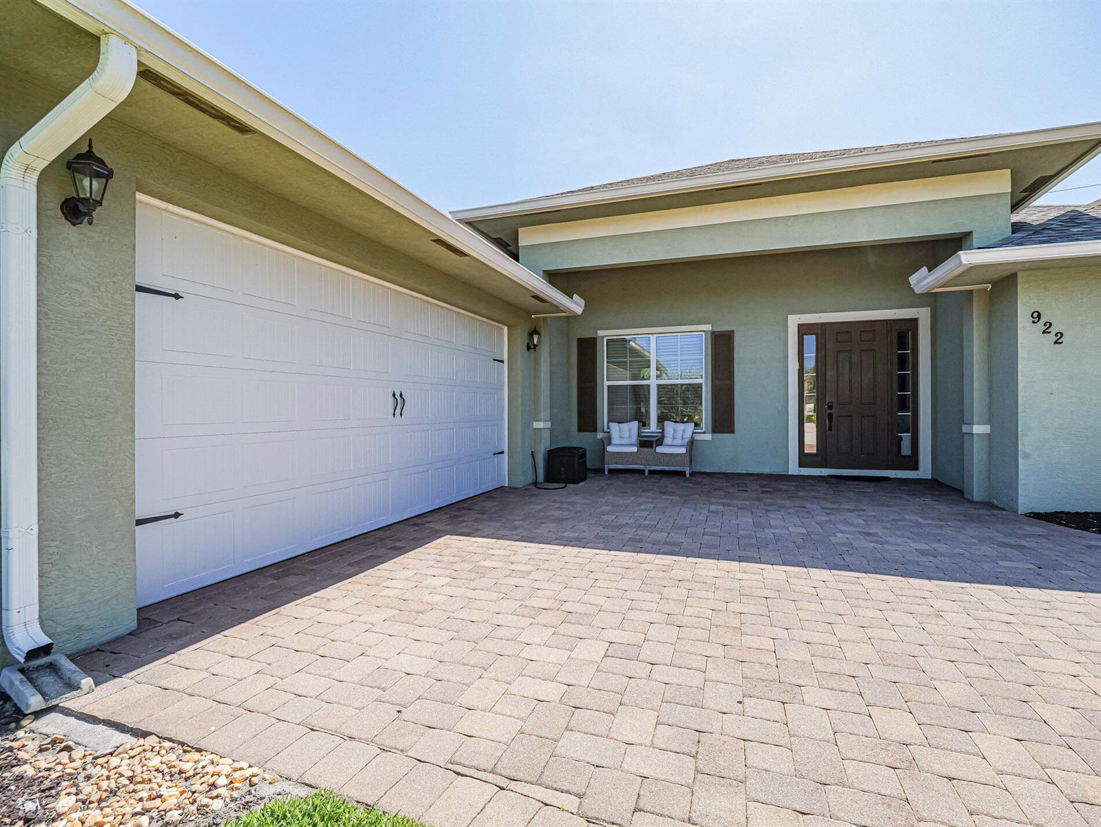 A paved driveway leads to a house with a white garage door and front entryway — 922 Yearling Trail, Sebastian FL 32958, SEBASTIAN, FL