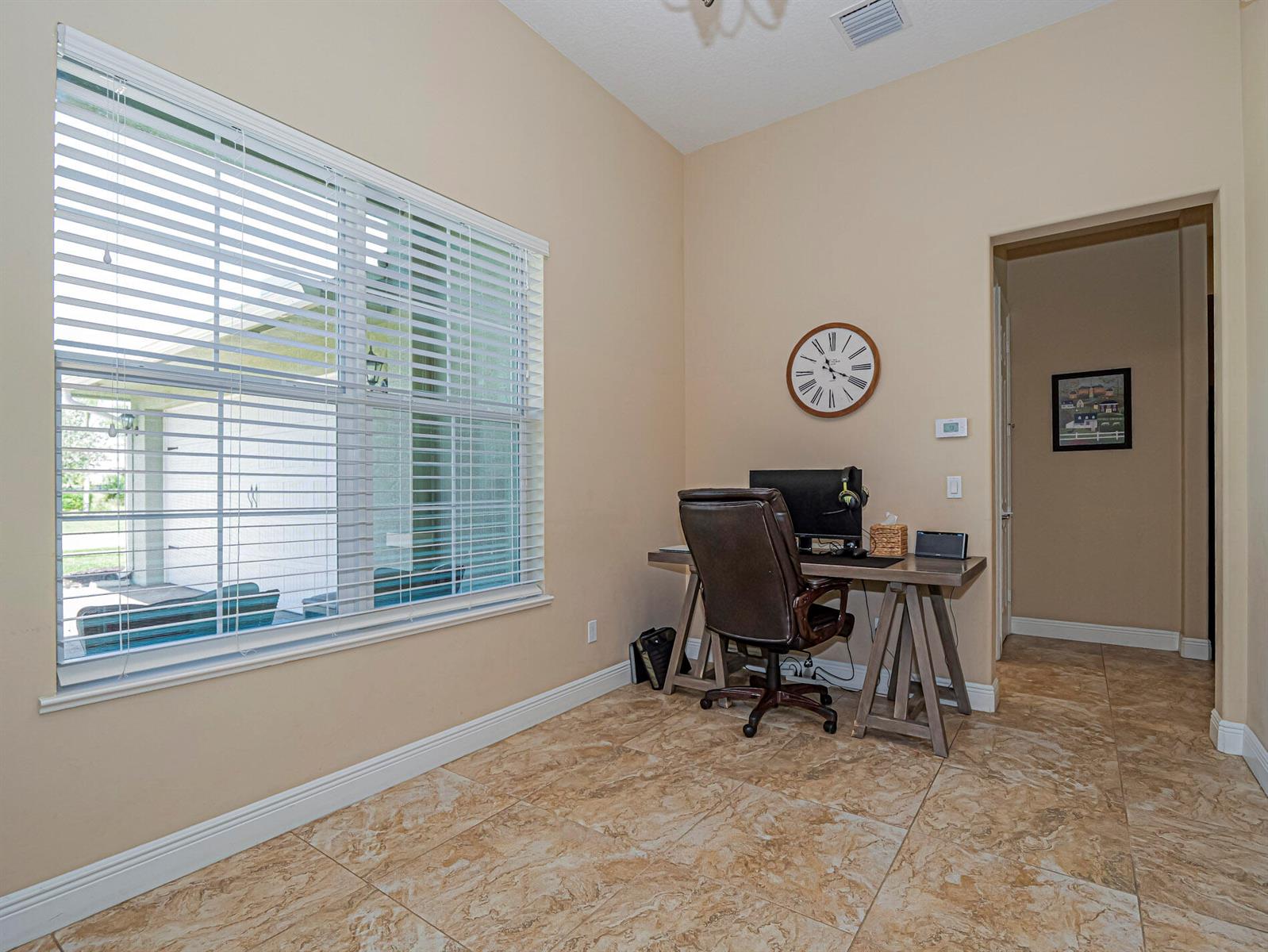 A home office features tile flooring, a desk with a chair, and a large window — 922 Yearling Trail, Sebastian FL 32958, SEBASTIAN, FL