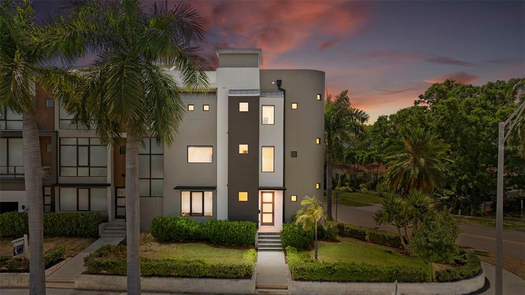 A modern three-story townhouse with a curved gray facade and palm trees at dusk — 92 W DAVIS BOULEVARD, TAMPA, FL