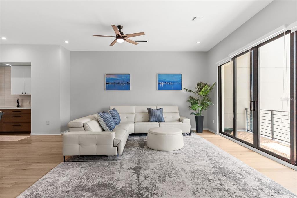 A living room features a white sectional sofa, a round ottoman, and a sliding glass door — 92 W DAVIS BOULEVARD, TAMPA, FL